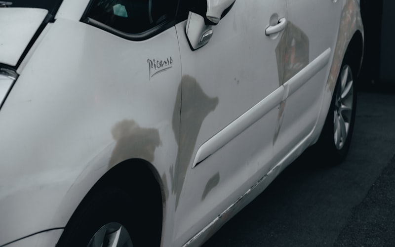 Delle und Einbeulung in der Flanke eines hellen Fahrzeugs